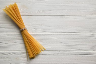 Spagetti Beyaz ahşap zemin üzerinde. Uzay kopyalayın. Üstten görünüm