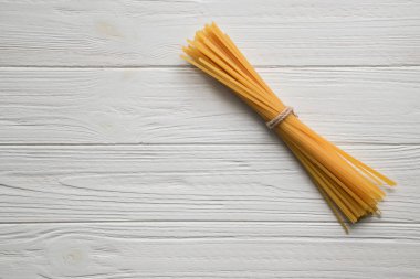 Spagetti Beyaz ahşap zemin üzerinde. Uzay kopyalayın. Üstten görünüm