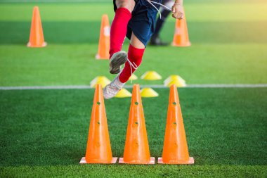 Çocuk futbol atlama ve marker koni arasında koşu.