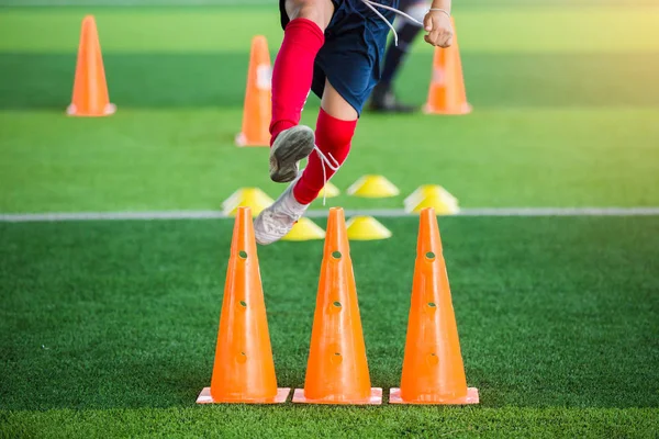 少年足球是跳跃和慢跑在标记锥体之间 — 图库照片