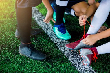 Çocuk futbol oyuncu sit ve daha önce eğitim futbol spor ayakkabı bağcığı bağlama.
