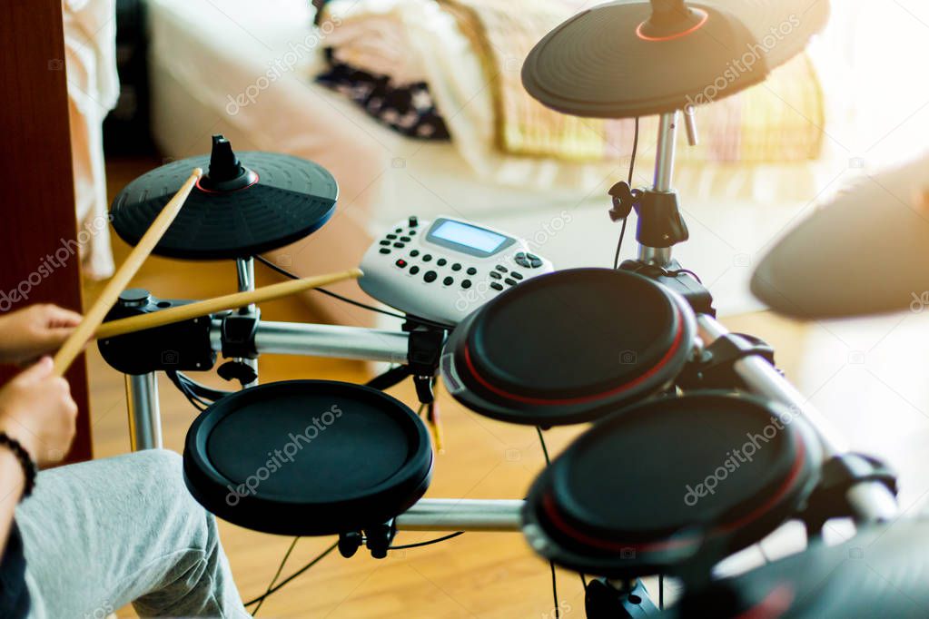 Asian girl put black tshirt and headphone learning and play electronic drum wooden drumsticks in home.