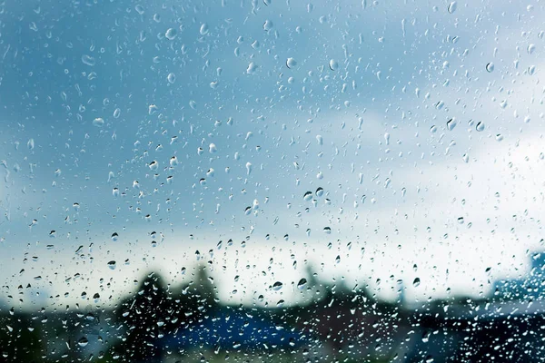 Water droplet on windshield with blurry blue sky background.