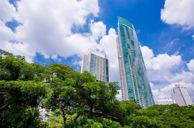 İş ofis gökdelenler ticaret bölgesi, mavi gökyüzü beyaz bulutlar, alt görünümü ile yükselterek mimari yüksek binalar bakarak taze yeşil ağaçlı.
