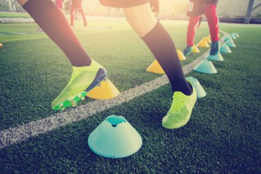 Genç çocuk futbol oyuncuları koşu ve birçok işaret koni arasında atlamak. Eğitim futbolcu.