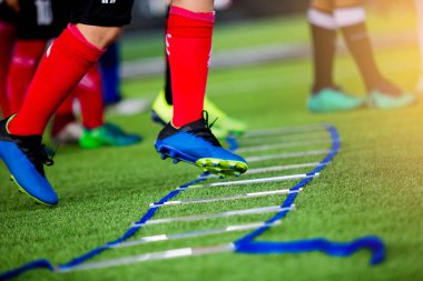 Genç çocuk futbol oyuncuları koşu ve merdiven matkaplar futbol eğitim için arasında atlamak. Merdiven egzersizleri futbol ya da futbol takımı için girer. Çocuk futbol oyuncu egzersizleri merdiven matkaplar Doğum.