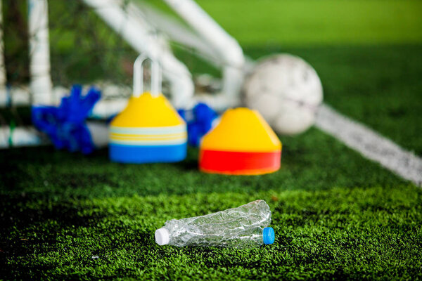 Plastic bottles with blurry soccer training equipment on artificial turf. It is waste from soccer training or football match.