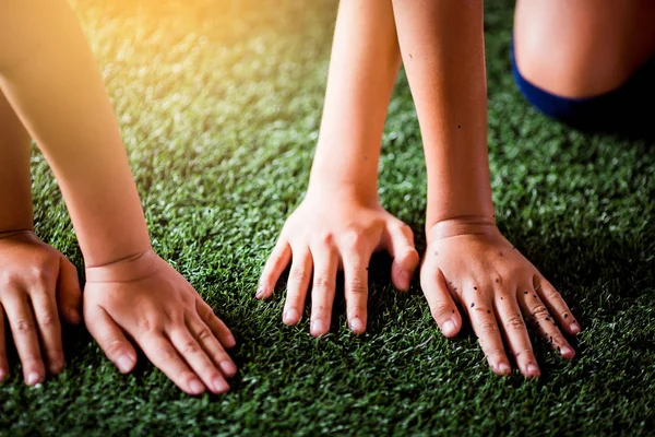 Children\'s hands on green artificial turf. Kid soccer training  football.