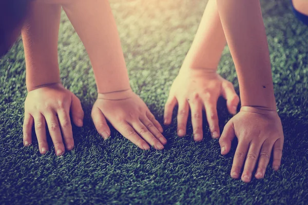 Children's hands on green artificial turf. Kid soccer training  football.