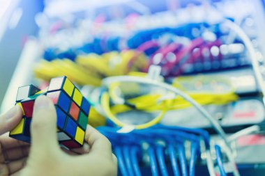 Bangkok, Tayland - 31 Ekim 2018: Rubik küpü - teknik ve çözme sorun ve beyin eğitimi kavramı ile bilgisayar ağ bulanık arka plan iş tutan bilgisayar teknisyen.