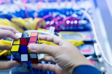 Bangkok, Tayland - 31 Ekim 2018: Rubik küpü - teknik ve çözme sorun ve beyin eğitimi kavramı ile bilgisayar ağ bulanık arka plan iş tutan bilgisayar teknisyen.