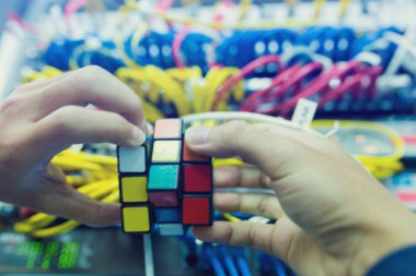 Bangkok, Tayland - 31 Ekim 2018: Rubik küpü - teknik ve çözme sorun ve beyin eğitimi kavramı ile bilgisayar ağ bulanık arka plan iş tutan bilgisayar teknisyen.