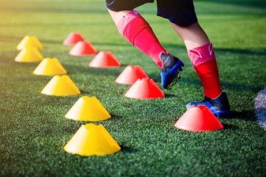 Futbolcu koşu ve futbol eğitim için yeşil suni çim üzerinde koni işaretleri arasında atlamak. Futbol ya da futbol Akademisi.