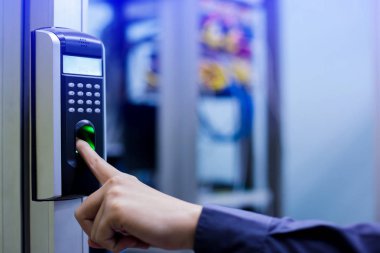 Personel, kontrol odasının ya da veri merkezinin kapısına ulaşmak için parmak taramasıyla elektronik kontrol makinesine basıyor. Veri güvenliği veya veri erişim denetimi kavramı.