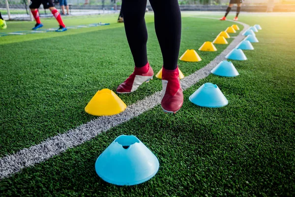 足球运动员慢跑和跳跃之间的锥形标记上绿色人造草皮足球训练 足球或足球学院 — 图库照片
