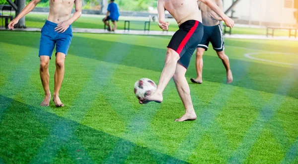 Soccer players not wearing a sport shirt and barefoot do trap and control the ball for shoot to goal. Soccer players fighting each other by kicking the ball.