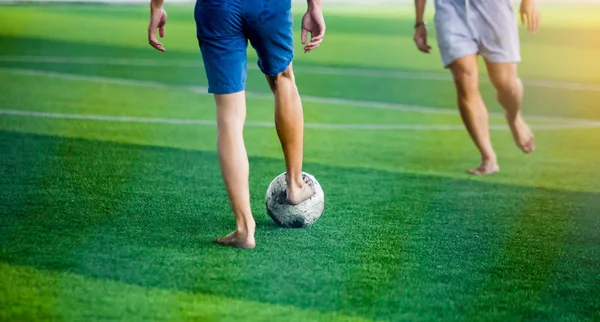 Soccer players not wearing a sport shirt and barefoot do trap and control the ball for shoot to goal. Soccer players fighting each other by kicking the ball.