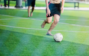 Bir spor gömlek ve yalınayak takmayan futbolcular hız çalıştırmak hedefe yeşil suni çim üzerinde topa vurmaya. Topu tekmeleme tarafından birbirlerinizle futbolcular.