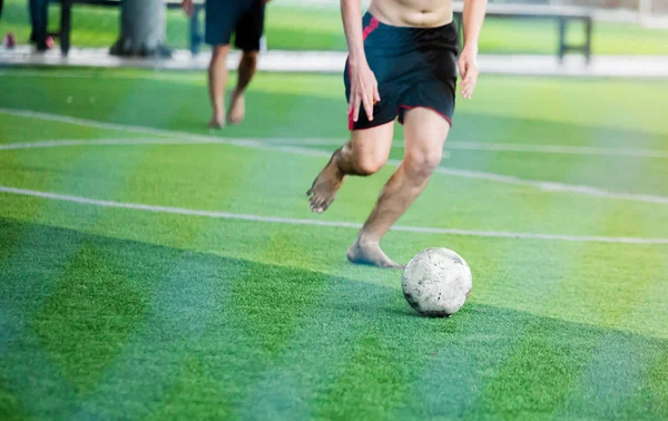 サッカー選手スポーツ シャツと裸足は身に着けていない緑の人工芝上にゴールにボールを撮影する速度を実行します ボールを蹴ることによって互いを戦うサッカー選手 — ストック写真