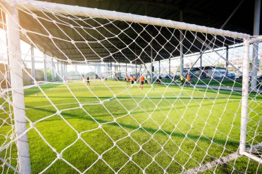 Beyaz kafes amacı ile koç ile yeşil yapay çim üzerinde oturan bulanık genç çocuk futbol oyuncuları.