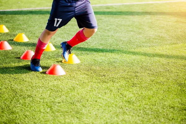 足球运动员慢跑和跳跃之间的锥形标记上绿色人造草皮足球训练 足球或足球学院 — 图库照片