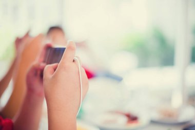 Asyalı çocuk oyun smartphone ile kulaklık ve arkadaşları için oyun ve eğlence restoranda yemek masasında