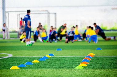 Futbol antrenmanı Ekipmanı eğitim arka plan bulanık çocuk oyuncular ile yeşil suni çim üzerinde koni işaretleri var. Futbol Akademisi mezunlarını bilinçlendirilmesini için malzeme