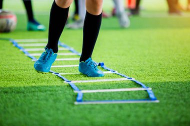 Genç çocuk futbol oyuncuları koşu ve merdiven matkaplar futbol eğitim için arasında atlamak. Merdiven egzersizleri futbol ya da futbol takımı için girer. Çocuk futbol oyuncu egzersizleri merdiven matkaplar Doğum.