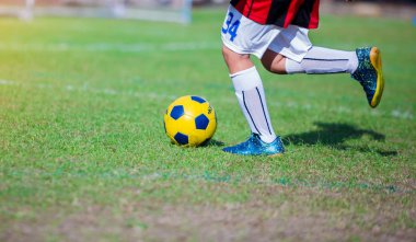 Çocuk futbol oyuncu hız çalıştırmak hedefe yeşil çimenlerin üzerinde topa vurmaya. Futbol oyuncu eğitim veya futbol maç.