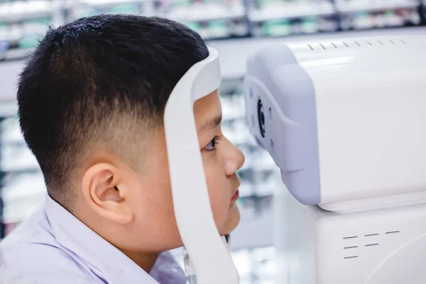 eyesight check. Asian boys checking eyesight and vision correction. Medical treatment and rehabilitation. Ophthalmology clinic concept - Boy doing checking vision by modern electronic technology