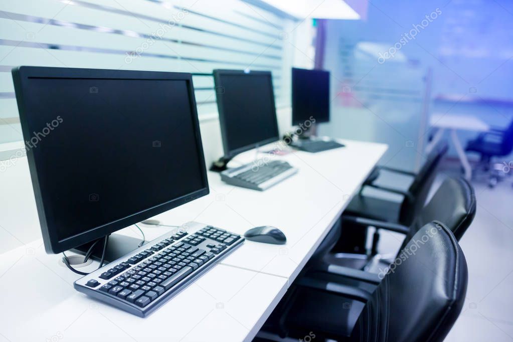 composite image of computer in office or training room. the computer is on the table in a bright interior. white desk and black revolving chair with computer pc and mouse in office.