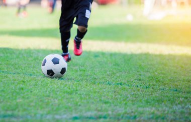 Çocuk futbol oyuncu hız çalıştırmak hedefe yeşil çimenlerin üzerinde topa vurmaya. Futbol maçı için eğitim futbolcu