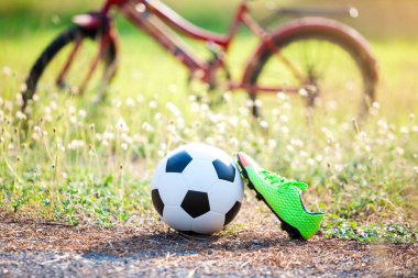 Futbol ve futbol ayakkabı ile bulanık kırmızı bisiklet ve açık spor için yeşil çim
