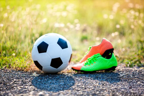 football and soccer shoes with blurry of green grass for soccer player training and playing football.