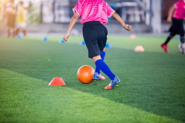 Futbol oyuncu atlama ve stomp yakalamak eğitim ve denetim futbol. Futbol oyuncuları evlat koşu ve atlama arasında koni futbol eğitim için işaretleyici.