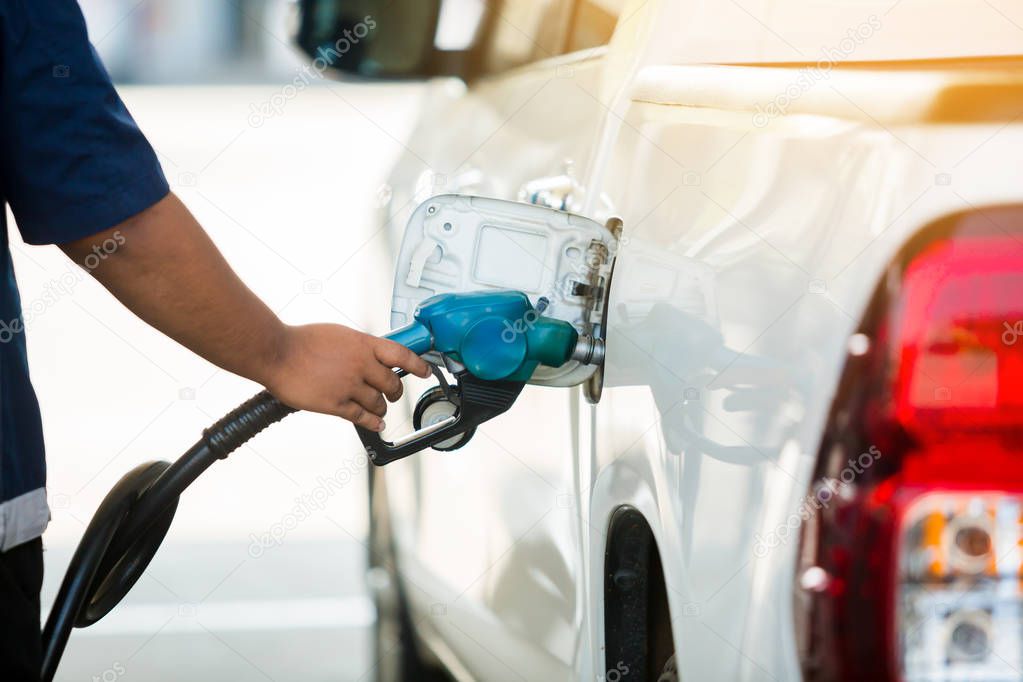 Hand refilling the white pickup truck with fuel at the gas station. Oil and gas energy.