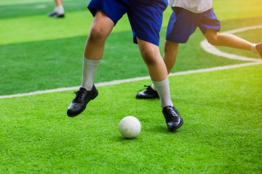 Asyalı öğrenci plastik futbol topu yeşil yapay çim üzerinde oynamak. Genç çocuk futbolcular plastik topu tekmeleme tarafından kavga.