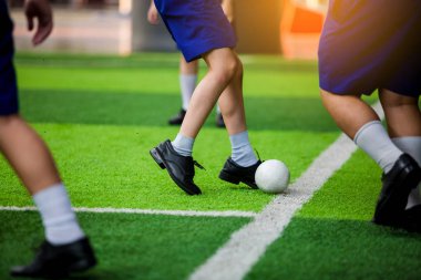 Asyalı öğrenci plastik futbol topu yeşil yapay çim üzerinde oynamak. Genç çocuk futbolcular plastik topu tekmeleme tarafından kavga.