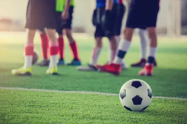 Eğitim ve başlangıç oyun önce ayakta bulanık futbolcular ile yeşil yapay çim futbol topu.