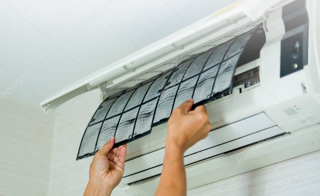 selective focus to left hand of male technician cleaning air conditioner indoors with a lot of dust. Basic cleaning dust in air conditioner at home with yourself.