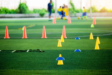 Futbol antrenmanı ekipmanı eğitim arka plan bulanık çocuk oyuncular ile yeşil suni çim üzerinde koni işaretleri var. Futbol Akademisi Eğitim sınıfı için malzeme