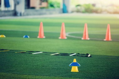 Futbol antrenmanı ekipmanı eğitim arka plan bulanık çocuk oyuncular ile yeşil suni çim üzerinde koni işaretleri var. Futbol Akademisi Eğitim sınıfı için malzeme