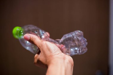 adam elini tutun ve kırma plastik şişe, plastik geri dönüşüm