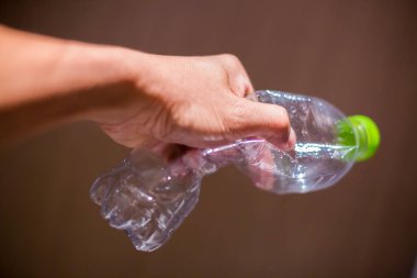 adam elini tutun ve kırma plastik şişe, plastik geri dönüşüm