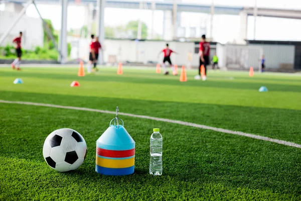 soccer ball, marker cones and bottle water on green artificial turf for soccer training.