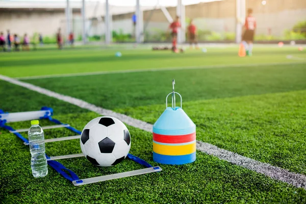 soccer ball, ladder drill, marker cones and bottle water on green artificial turf for soccer training equipment.