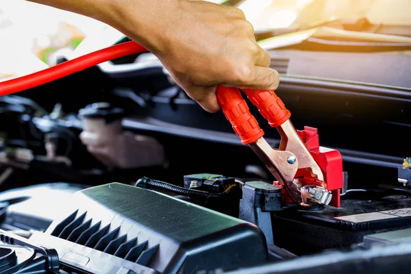 selective focus charging car with electricity trough cables. first connect anode then follow connect negative connector battery