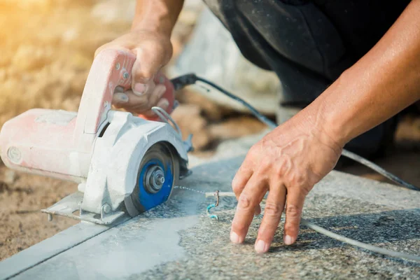 worker cutting granite stone with an diamond electric saw blade and use water to prevent dust and heat at a construction site