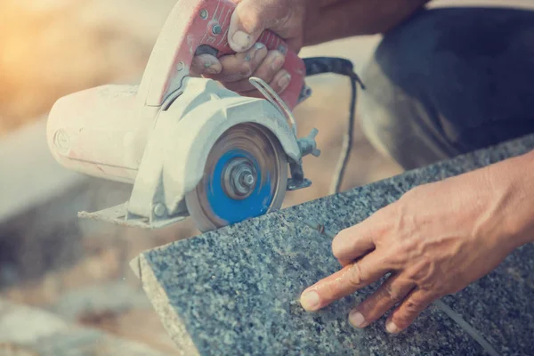worker cutting granite stone with an diamond electric saw blade and use water to prevent dust and heat at a construction site