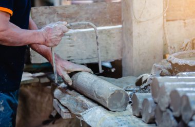 Atölyesinde heykel için silindir kil kesme